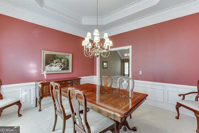 dining space with light colored carpet, a raised ceiling, crown molding, and an inviting chandelier