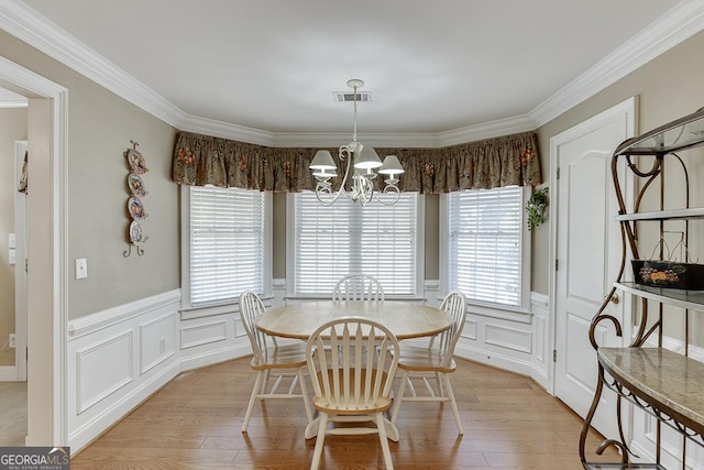 dining area featuring crown molding, an inviting chandelier, light wood-style floors, and a healthy amount of sunlight