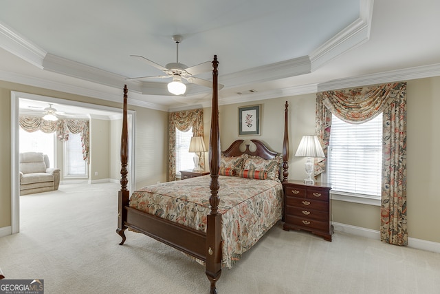 carpeted bedroom with ceiling fan, crown molding, and a tray ceiling