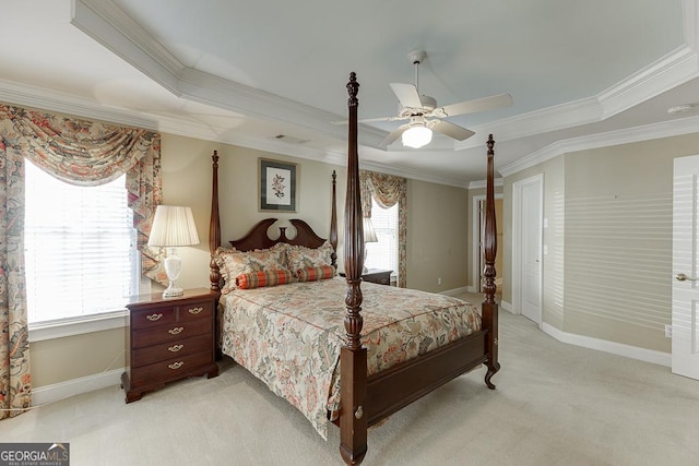bedroom featuring light carpet, a tray ceiling, baseboards, a ceiling fan, and ornamental molding
