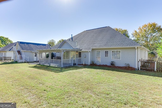 back of house with fence, a lawn, and roof with shingles