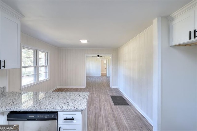 kitchen featuring light hardwood / wood-style flooring, white cabinets, stainless steel dishwasher, and light stone counters