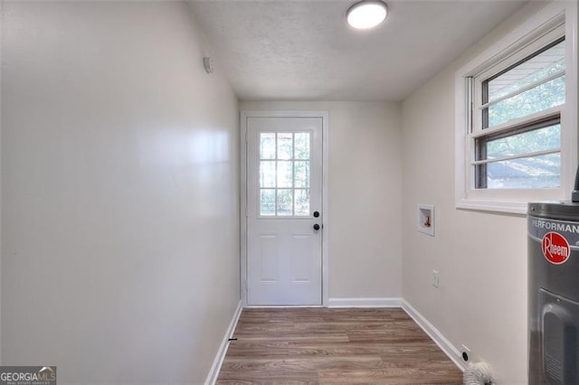 doorway with a wealth of natural light, hardwood / wood-style floors, and water heater