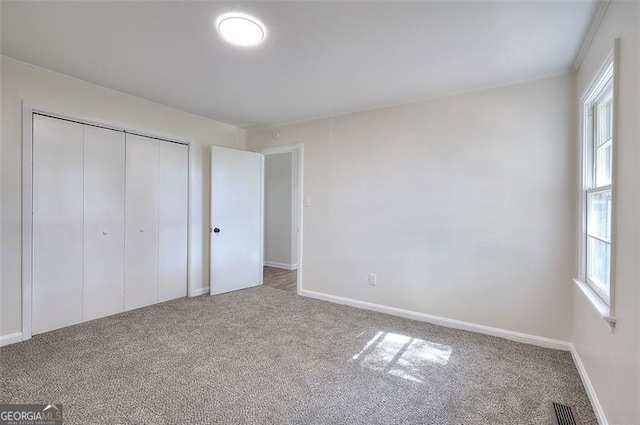 unfurnished bedroom featuring multiple windows, a closet, and carpet flooring