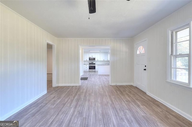 foyer featuring light hardwood / wood-style flooring, ornamental molding, and wood walls