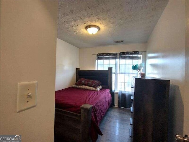 bedroom with dark wood-type flooring and a textured ceiling