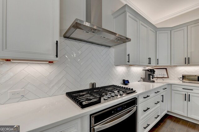 kitchen featuring stainless steel appliances, wall chimney exhaust hood, white cabinets, dark wood-type flooring, and decorative backsplash