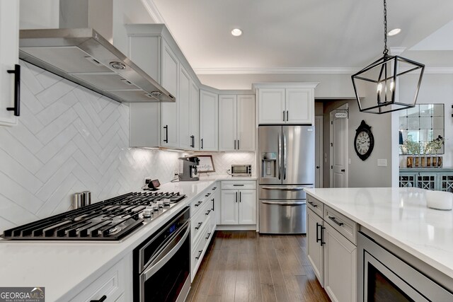 kitchen featuring wall chimney exhaust hood, dark wood-type flooring, hanging light fixtures, stainless steel appliances, and light stone countertops