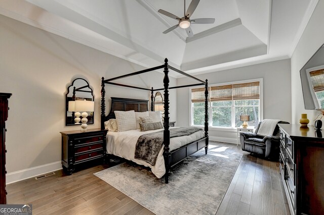 bedroom with crown molding, dark hardwood / wood-style floors, a raised ceiling, and ceiling fan