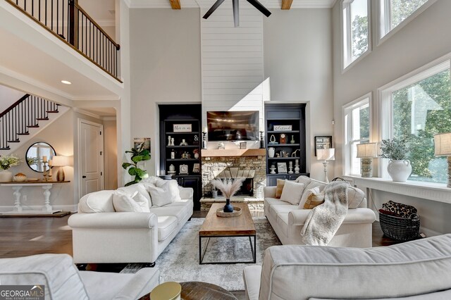 living room with high vaulted ceiling, beamed ceiling, a fireplace, and hardwood / wood-style floors