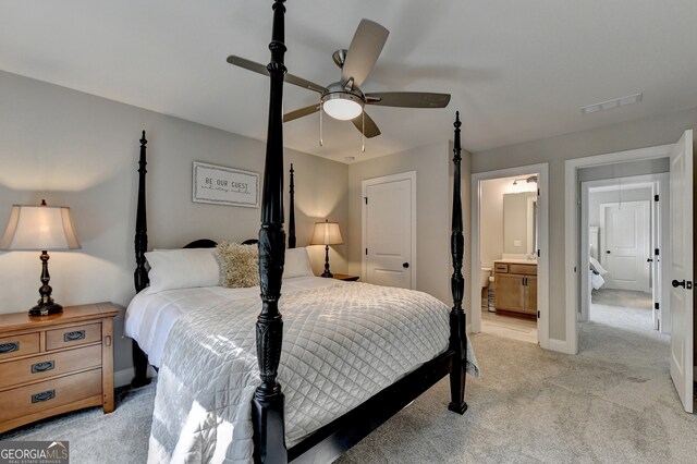 bedroom with ceiling fan, light carpet, and ensuite bath