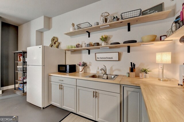 kitchen with white fridge, wood counters, sink, and gray cabinetry