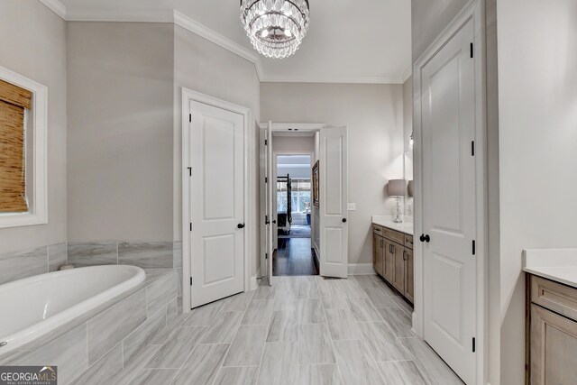 bathroom with hardwood / wood-style flooring, tiled tub, ornamental molding, an inviting chandelier, and vanity