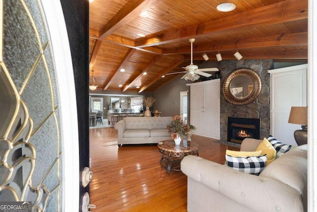 living room featuring vaulted ceiling with beams, a fireplace, wood ceiling, ceiling fan, and hardwood / wood-style flooring