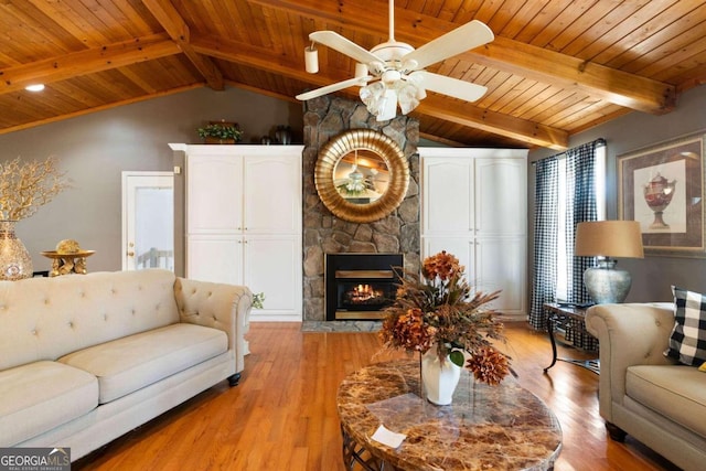 living room featuring vaulted ceiling with beams, a fireplace, light hardwood / wood-style floors, and wooden ceiling