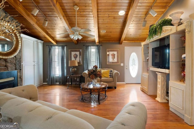 living room with a fireplace, light hardwood / wood-style floors, ceiling fan, beamed ceiling, and wooden ceiling