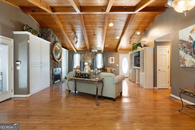 living room with lofted ceiling with beams, a fireplace, light wood-type flooring, and wooden ceiling