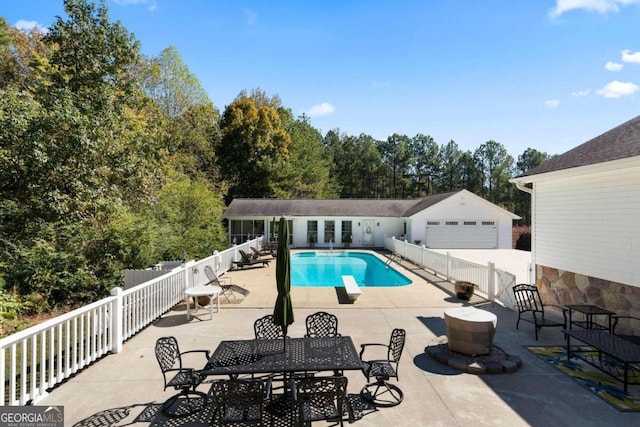 view of pool with a patio area, an outbuilding, a diving board, and a garage