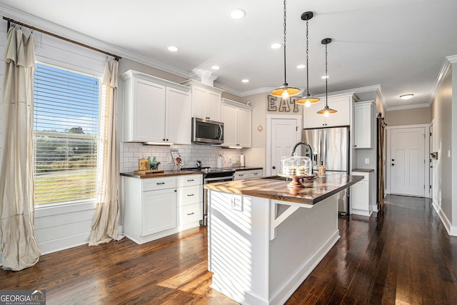 kitchen featuring appliances with stainless steel finishes, an island with sink, wood counters, and dark hardwood / wood-style flooring