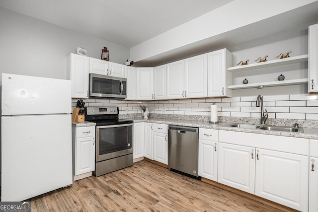 kitchen featuring sink, backsplash, stainless steel appliances, white cabinets, and light hardwood / wood-style flooring