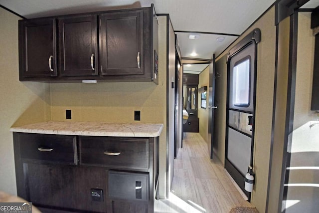 kitchen with dark brown cabinetry and light wood-type flooring