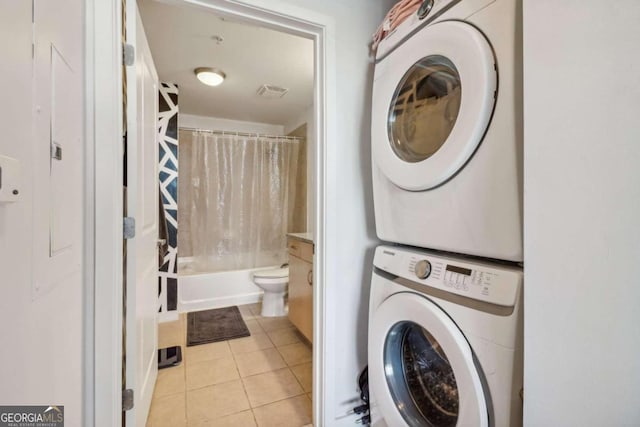 laundry area featuring light tile patterned flooring and stacked washer and clothes dryer