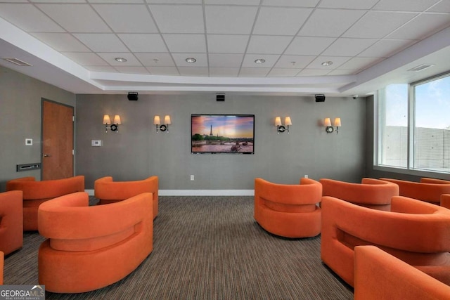 cinema room featuring a paneled ceiling, a raised ceiling, and dark carpet