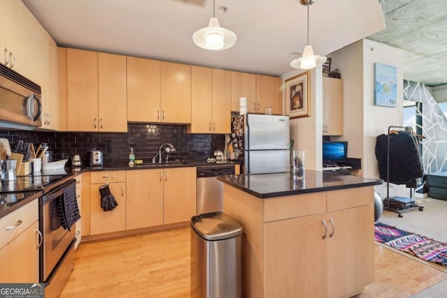 kitchen with stainless steel appliances, sink, light brown cabinets, and decorative light fixtures