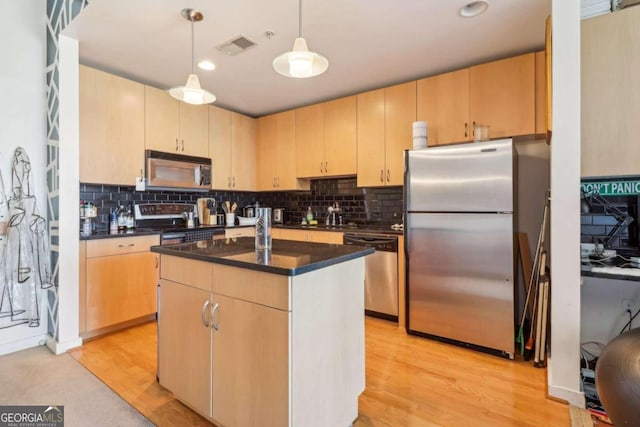 kitchen featuring hanging light fixtures, stainless steel appliances, light hardwood / wood-style floors, a kitchen island, and light brown cabinetry
