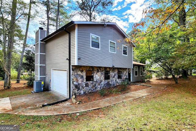 view of home's exterior featuring a garage, cooling unit, and a lawn