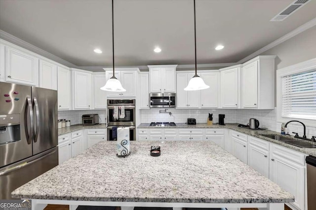 kitchen featuring white cabinetry, appliances with stainless steel finishes, a center island, and pendant lighting