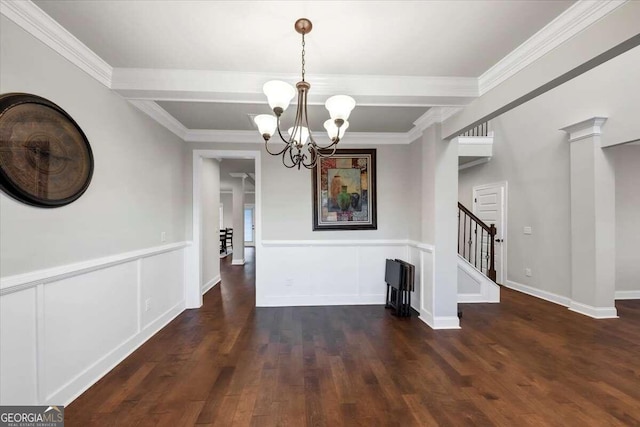 unfurnished dining area featuring ornamental molding, dark wood-type flooring, a notable chandelier, and decorative columns