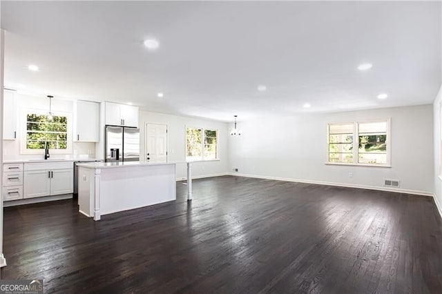 kitchen featuring stainless steel fridge with ice dispenser, plenty of natural light, a kitchen island, and dark hardwood / wood-style flooring