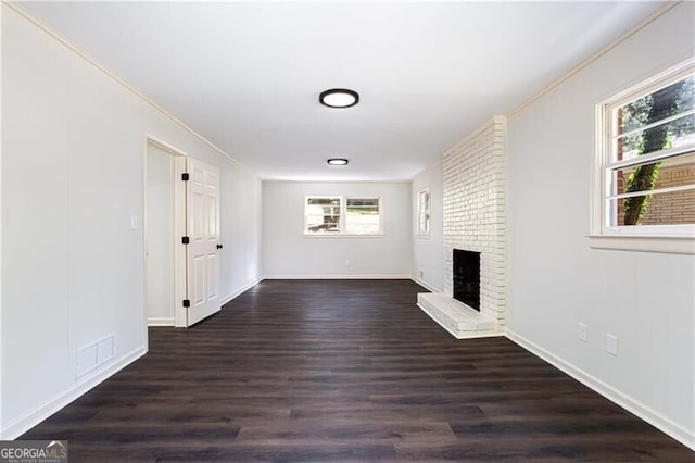 504 Milligan Dr, Stone Mountain, GA 30083 - unfurnished living room with a brick fireplace, dark wood-style floors, baseboards, and crown molding