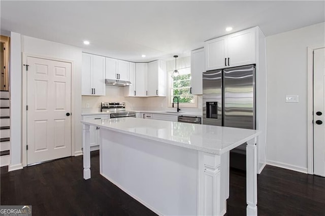 kitchen with dark wood-type flooring, sink, white cabinets, pendant lighting, and appliances with stainless steel finishes