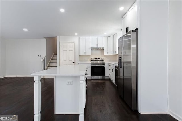 504 Milligan Dr, Stone Mountain, GA 30083 - kitchen featuring appliances with stainless steel finishes, dark wood-type flooring, light countertops, a kitchen island, and recessed lighting