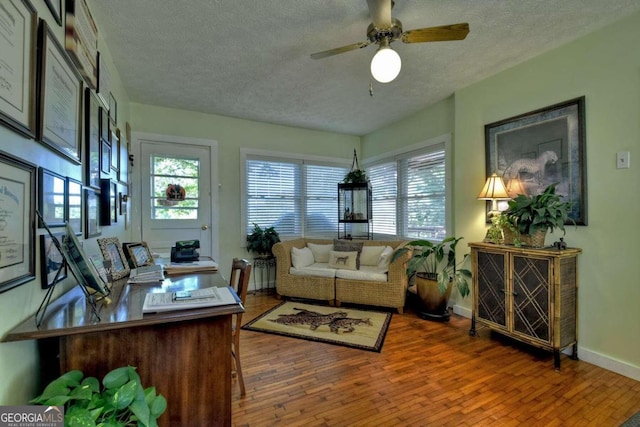 living room with a textured ceiling, wood-type flooring, and ceiling fan