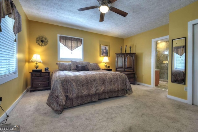 bedroom with ensuite bathroom, multiple windows, light colored carpet, and ceiling fan