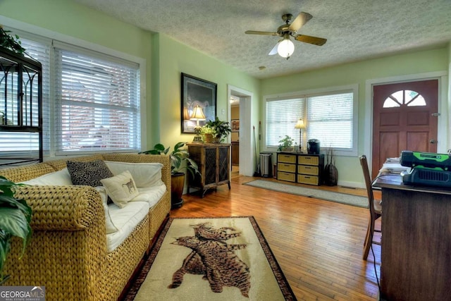 living room with a textured ceiling, wood-type flooring, and ceiling fan