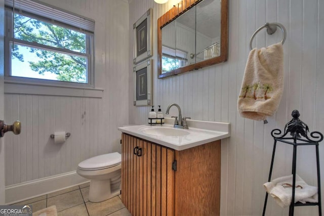 bathroom featuring vanity, toilet, wood walls, and tile patterned flooring