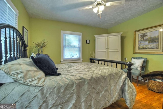 bedroom with ceiling fan, wood-type flooring, and a textured ceiling