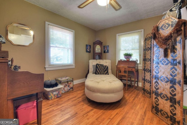 sitting room featuring light hardwood / wood-style floors, a textured ceiling, baseboard heating, and ceiling fan