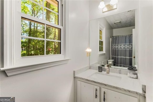 bathroom with a shower with shower curtain, vanity, and toilet