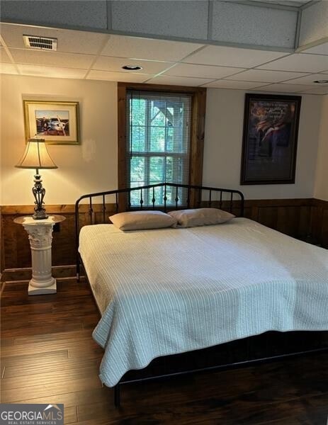 bedroom with wood-type flooring and a drop ceiling