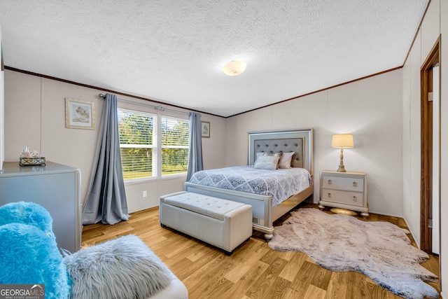 bedroom featuring ornamental molding, light hardwood / wood-style flooring, and a textured ceiling