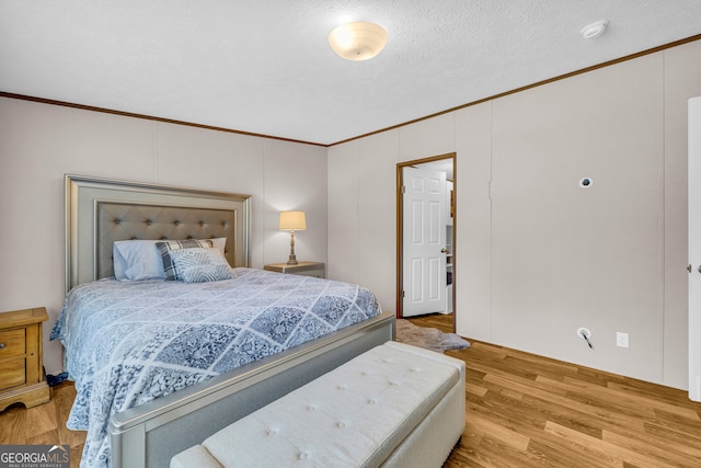 bedroom with crown molding, a textured ceiling, and light hardwood / wood-style flooring