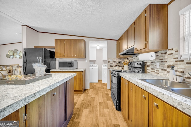 kitchen featuring black appliances, separate washer and dryer, lofted ceiling, crown molding, and light hardwood / wood-style flooring