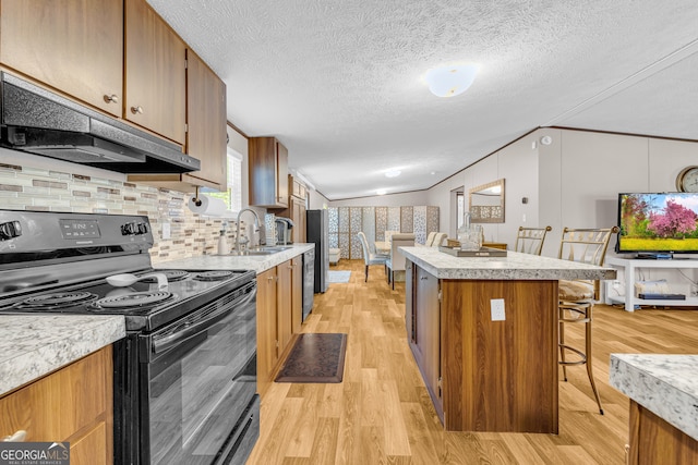 kitchen with a textured ceiling, electric range, a center island, light hardwood / wood-style floors, and a breakfast bar area