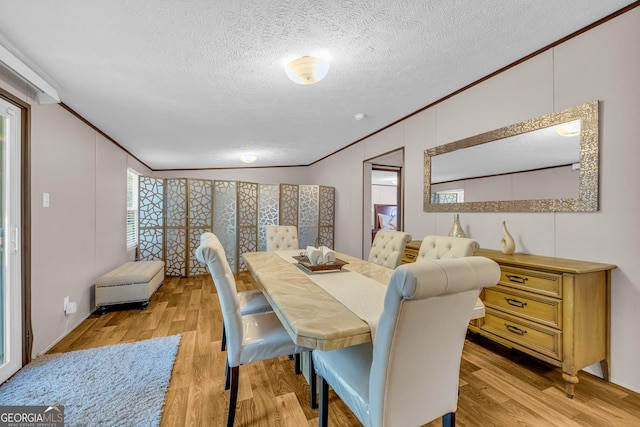 dining area with ornamental molding, a textured ceiling, and light wood-type flooring