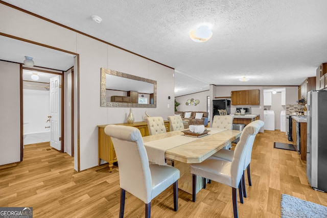 dining space featuring lofted ceiling, washer / clothes dryer, light hardwood / wood-style flooring, crown molding, and a textured ceiling